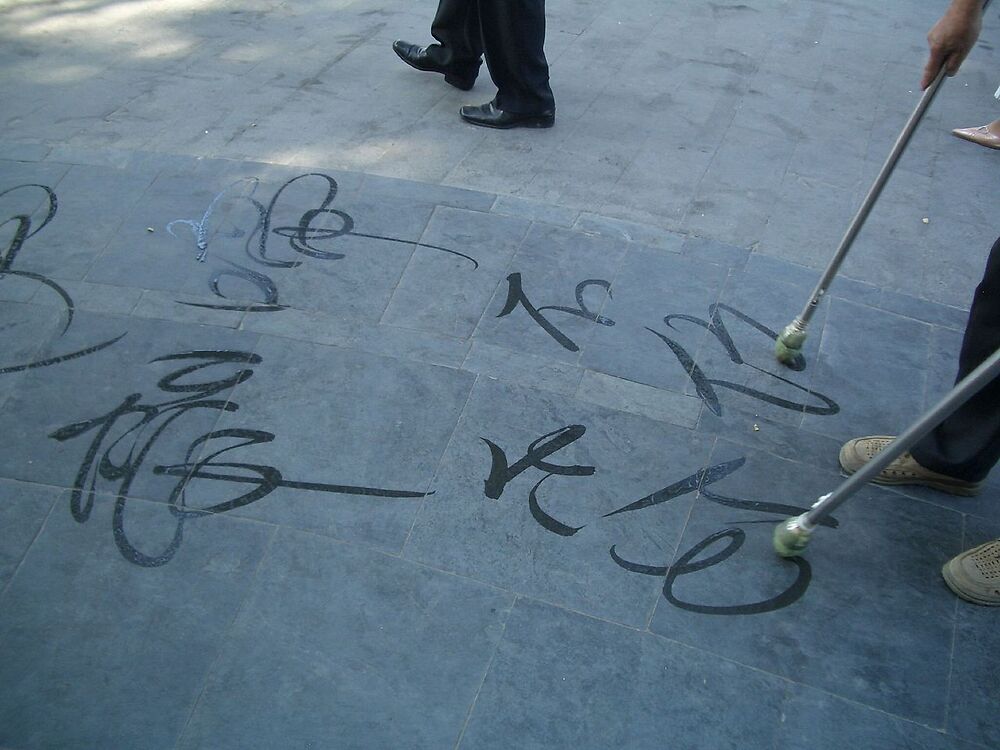 A man writing Chinese calligraphy with water brush at the Summer Palace in Beijing