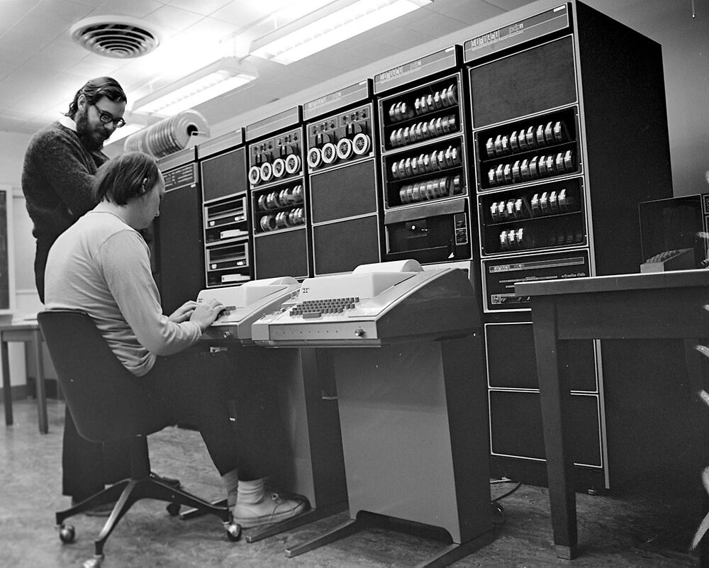 Ken Thompson sitting next to Dennis Ritchie in front of a PDP-11